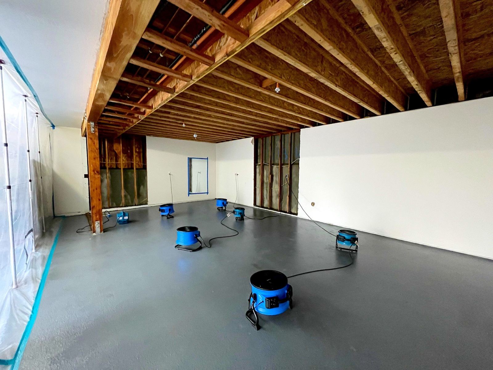 Air movers drying a room with exposed ceiling joists